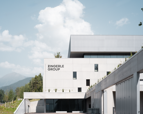 Firmengebäude des Hauptsitzes der Zingerle Group vor hellblauem Himmel, daneben eine Straße mit Grünstreifen