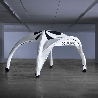 Weißes aufblasbares Zelt mit schwarzer Bedruckung und Vordach in leerer Produktionshalle