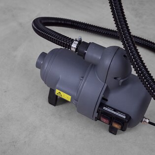 Nahaufnahme einer grauen elektrischen Pumpe mit schwarzem Pumpschlauch zum Aufbau eines aufblasbaren Zeltes