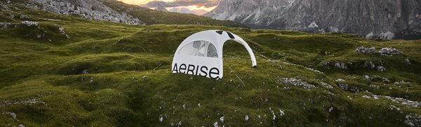Wide-angle aerial shot of a white inflatable tent with sidewall at dusk.