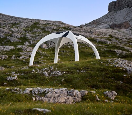 Weißes Zelt zum Aufblasen, schwarz bedruckt, im Hintergrund felsige Berglandschaft