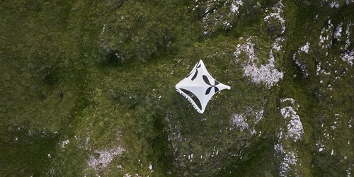 Weißes aufblasbares Zelt steht auf einer Bergwiese, fotografiert aus der Vogelperspektive
