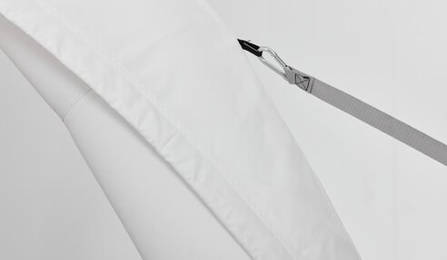 Ein weißes Zelt von Aerise ist mit einem Spanngurt am Untergrund befestigt