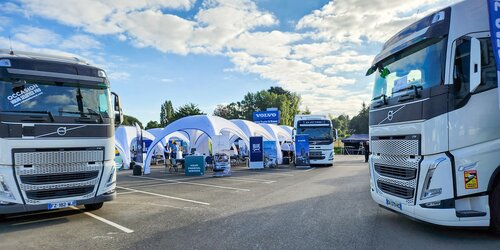 Mehrere weiße aufblasbare Eventzelte stehen auf einem Außengelände zwischen Volvo-Lastwagen.