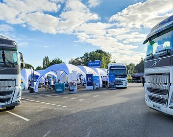 Mehrere weiße aufblasbare Eventzelte stehen auf einem Außengelände zwischen Volvo-Lastwagen.