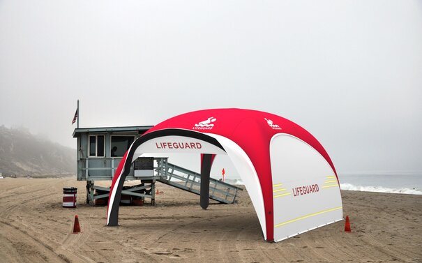 Aufblasbares Rettungszelte in den Farben Rot und Weiß mit Seitenwänden an Strand, trübes Wetter