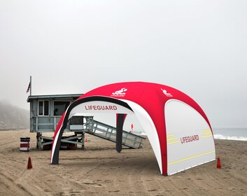 Aufblasbares Rettungszelte in den Farben Rot und Weiß mit Seitenwänden an Strand, trübes Wetter