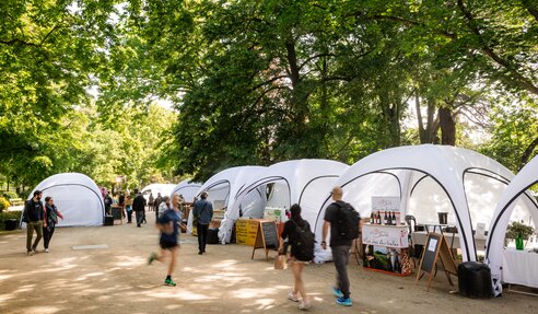 Mehrere weiße aufblasbare Zelte aneinandergereiht auf einem Markt für französische Spezialitäten.